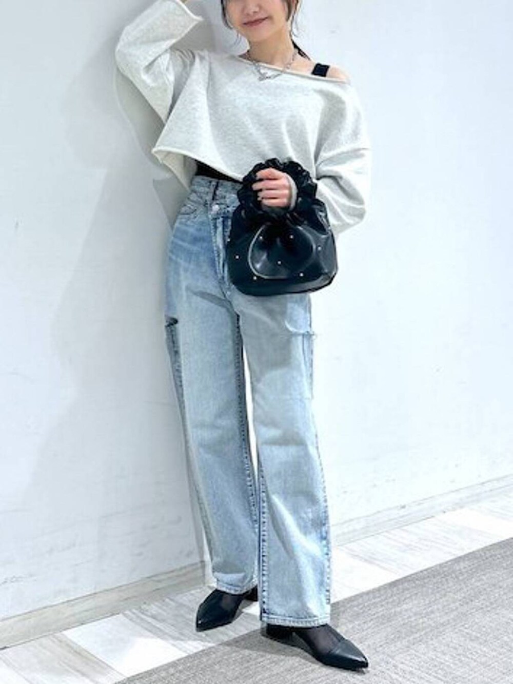 ブラック系のハンドバッグ、ブラック系のタンクトップ、ブルー系のデニムパンツを着用したレディースの冬コーディネートの5枚目の写真