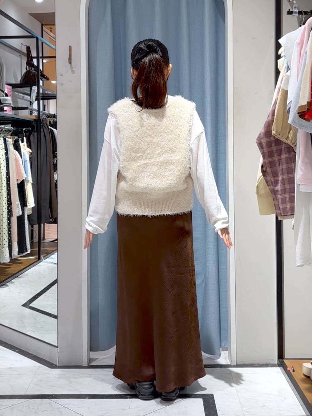 ブラウン系のスカート、ホワイト系のTシャツ/カットソー、ホワイト系のベストを着用したレディースの秋コーディネートの5枚目の写真