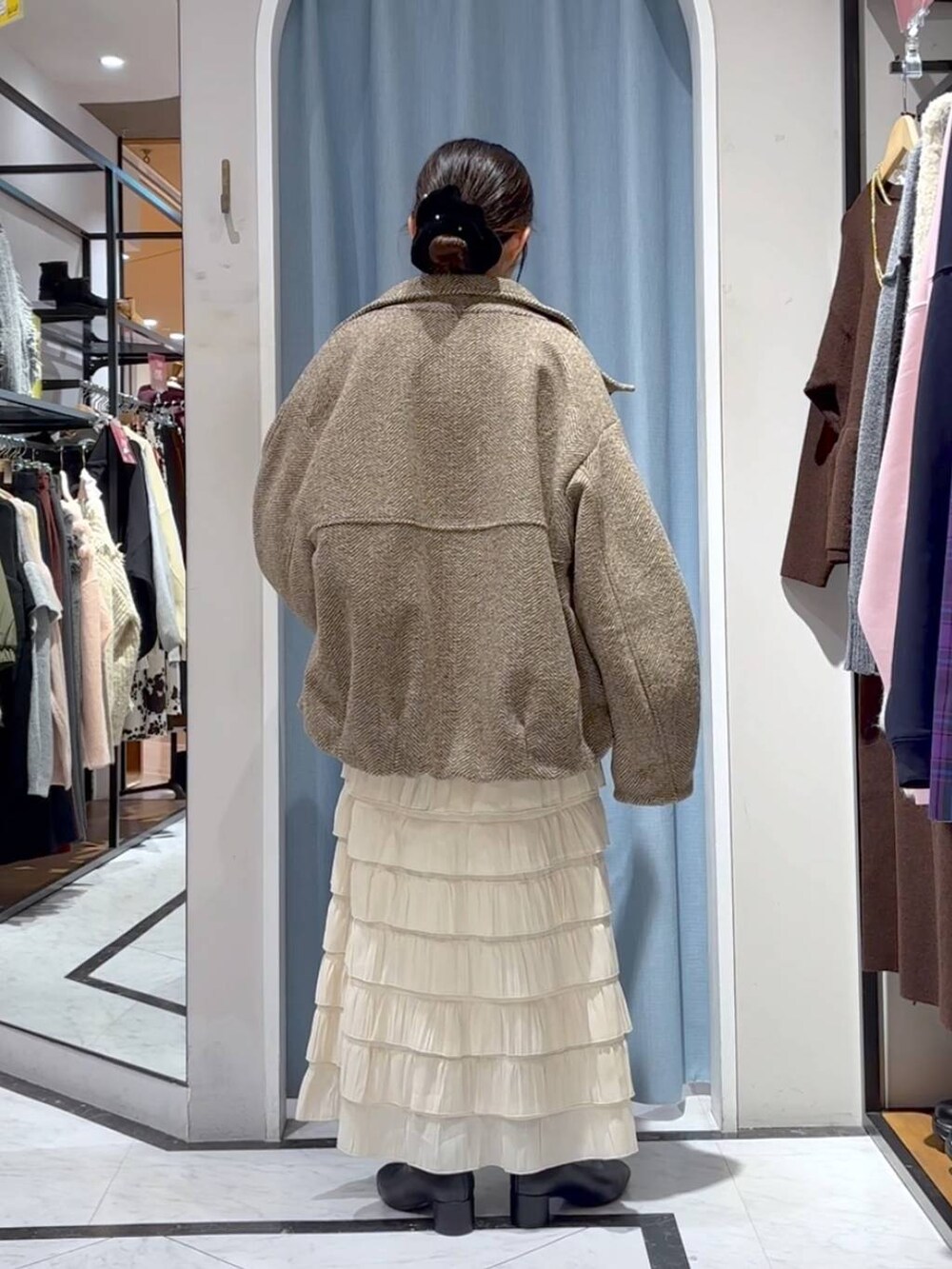 ベージュ系のブルゾン、ホワイト系のスカート、ブラウン系のニット/セーターを着用したレディースの冬コーディネートの8枚目の写真