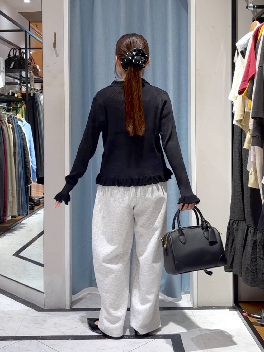 グレー系のスウェットパンツ、ブラック系のショルダーバッグ、ブラック系のニット/セーターを着用したレディースの秋コーディネートの7枚目の写真