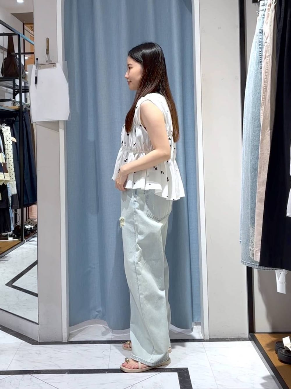 ブルー系のデニムパンツ、ホワイト系のサンダル、ホワイト系のシャツ/ブラウスを着用したレディースの夏コーディネートの5枚目の写真