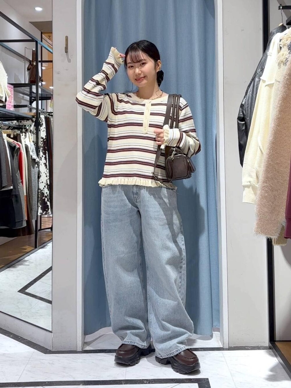 ブルー系のデニムパンツ、ブラウン系のボストンバッグ、ブラウン系のローファーを着用したレディースの冬コーディネートの3枚目の写真