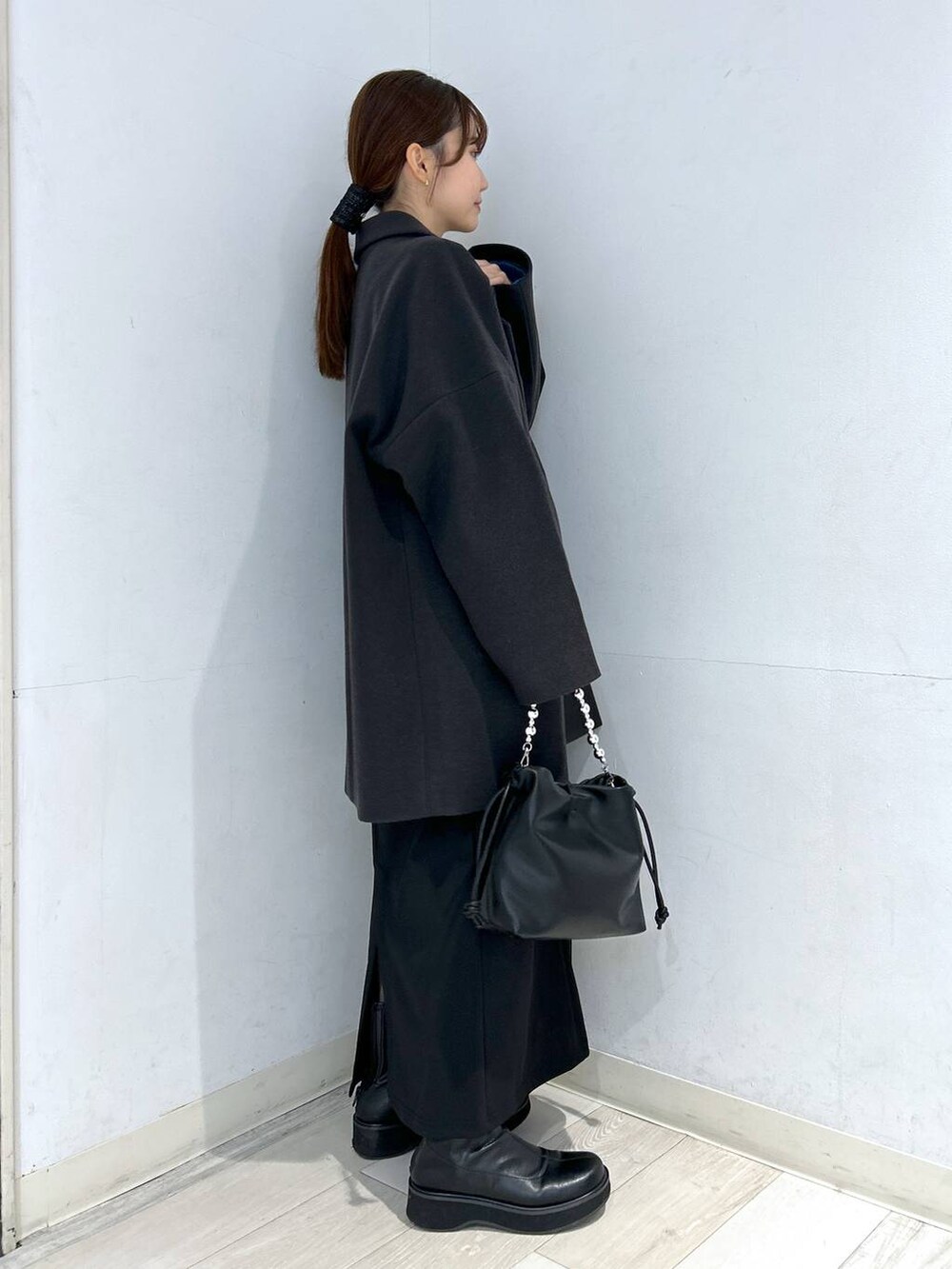 グレー系のステンカラーコート、ブラック系のブーツ、ブルー系のニット/セーターを着用したレディースの冬コーディネートの6枚目の写真