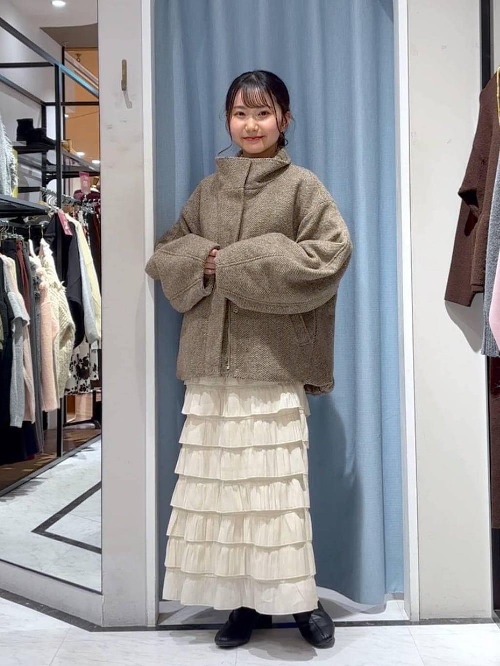 ベージュ系のブルゾン、ホワイト系のスカート、ブラウン系のニット/セーターを着用したレディースの冬コーディネートの2枚目の写真