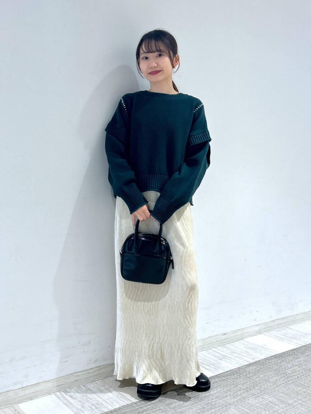 グリーン系のTシャツ/カットソー、ブラック系のブーツ、ブラック系のボストンバッグを着用したレディースの秋コーディネートの4枚目の写真