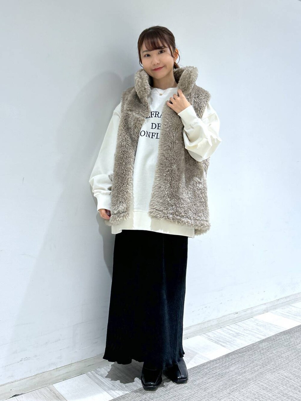 ホワイト系のブルゾン、ブラック系のパンプス、ブラック系のスカートを着用したレディースの冬コーディネートの2枚目の写真