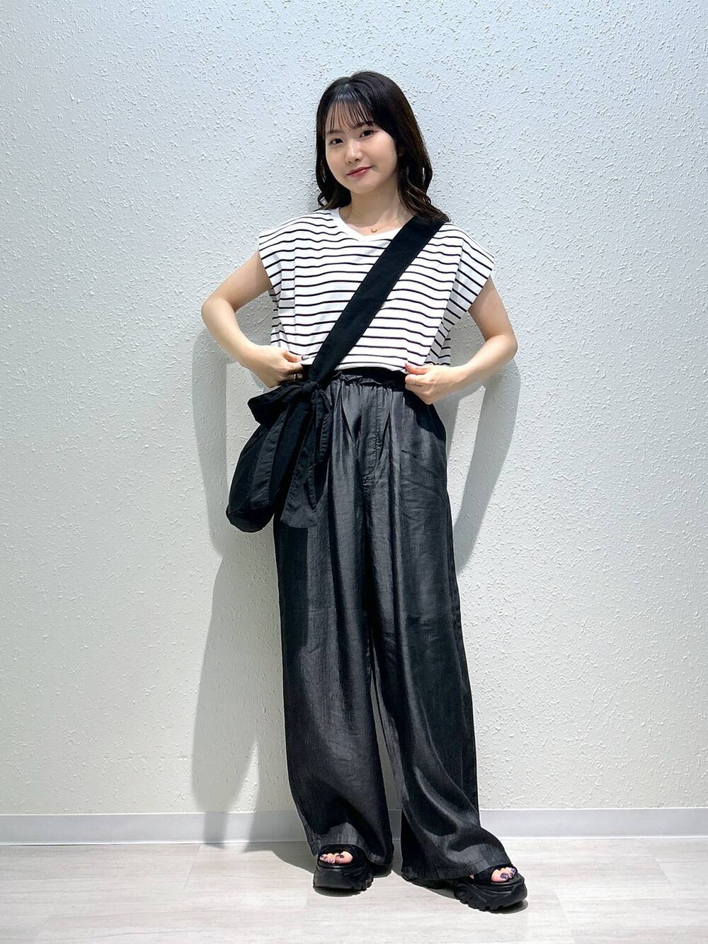 ブラック系のサンダル、ブラック系のデニムパンツ、ブラック系のTシャツ/カットソーを着用したレディースの夏コーディネートの3枚目の写真