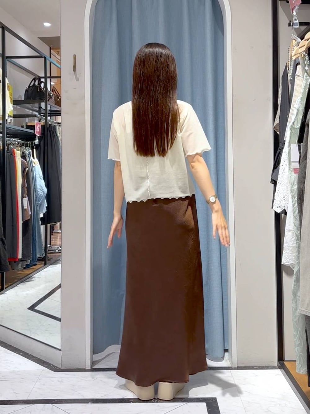 ホワイト系のTシャツ/カットソー、ホワイト系のサンダル、ブラウン系のスカートを着用したレディースの秋コーディネートの6枚目の写真