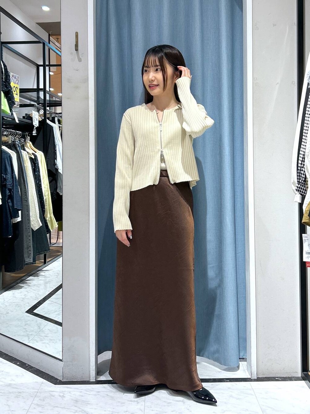 ホワイト系のカーディガン/ボレロ、ブラック系のパンプス、ゴールド系のタンクトップを着用したレディースの春コーディネートの6枚目の写真