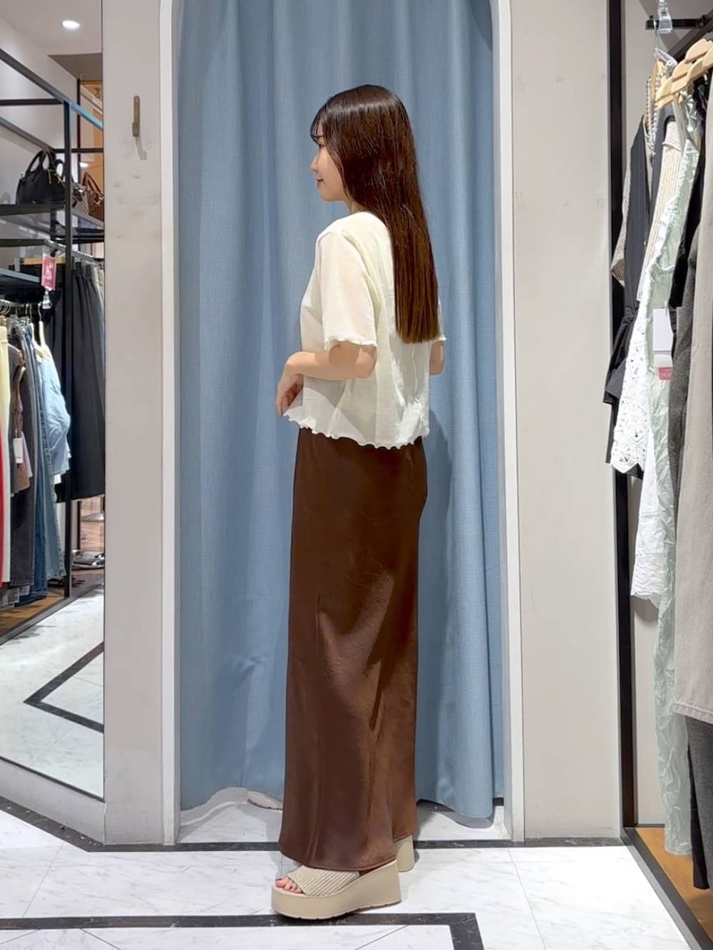 ホワイト系のTシャツ/カットソー、ホワイト系のサンダル、ブラウン系のスカートを着用したレディースの秋コーディネートの5枚目の写真