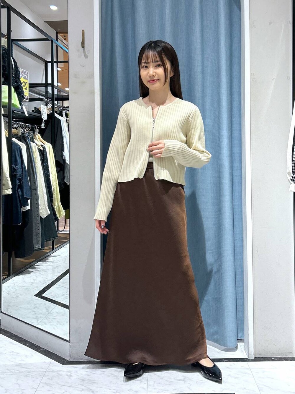 ホワイト系のカーディガン/ボレロ、ブラック系のパンプス、ゴールド系のタンクトップを着用したレディースの春コーディネートの7枚目の写真