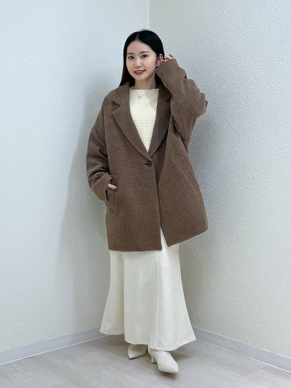 ホワイト系のスカート、ホワイト系のニット/セーター、その他のテーラードジャケットを着用したレディースの冬コーディネートの7枚目の写真