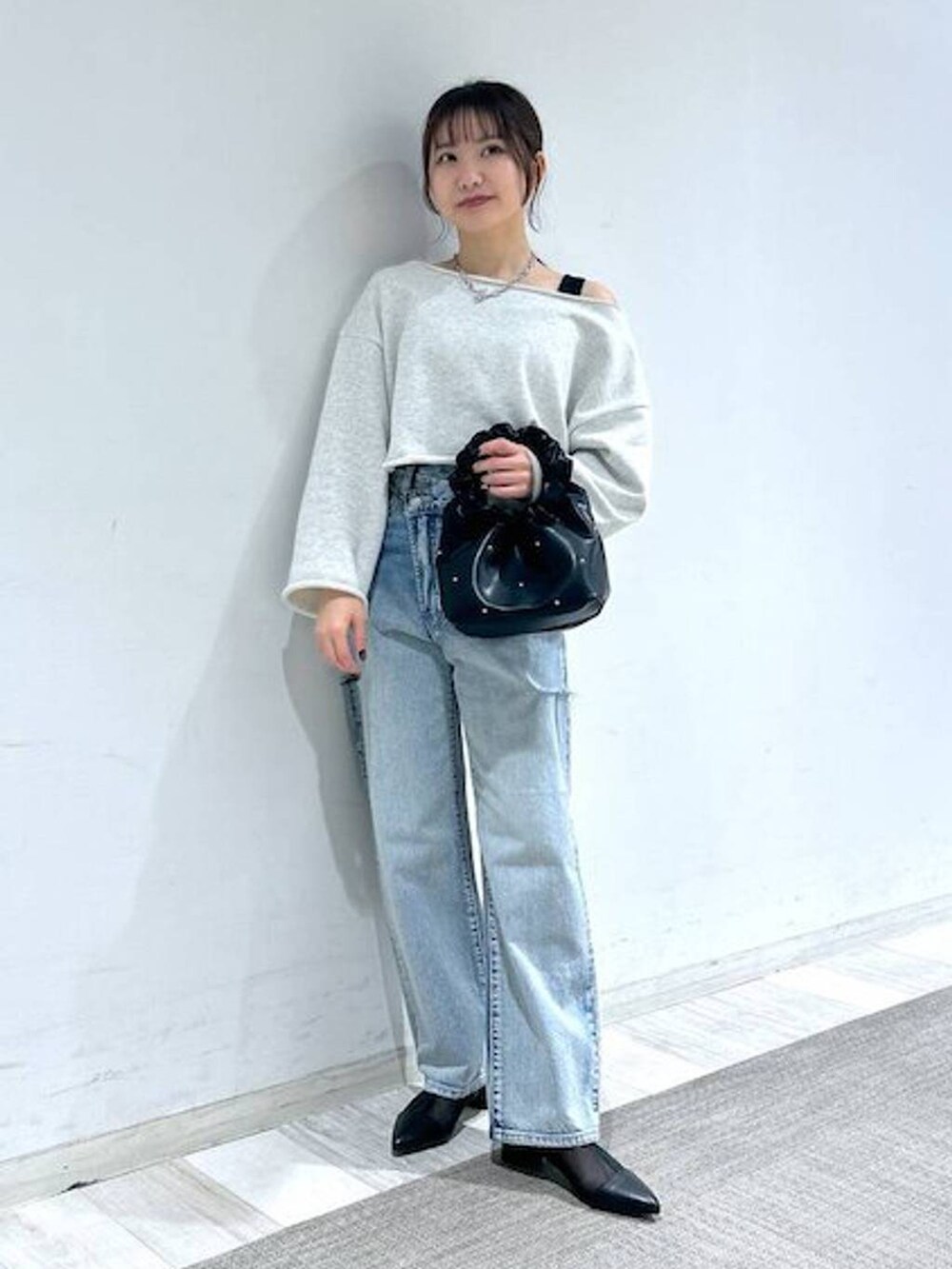 ブラック系のハンドバッグ、ブラック系のタンクトップ、ブルー系のデニムパンツを着用したレディースの冬コーディネートの3枚目の写真