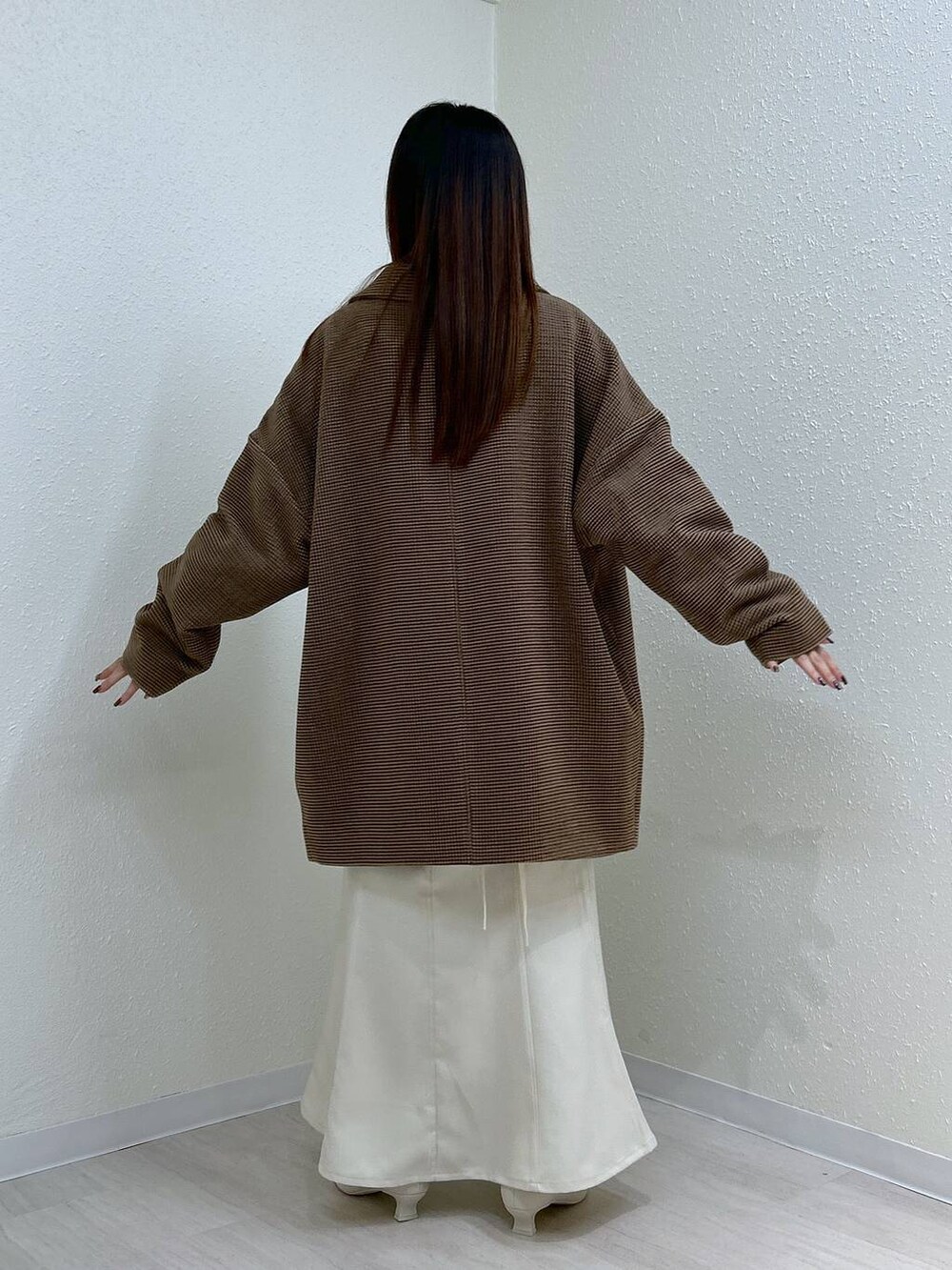 ホワイト系のスカート、ホワイト系のニット/セーター、その他のテーラードジャケットを着用したレディースの冬コーディネートの9枚目の写真