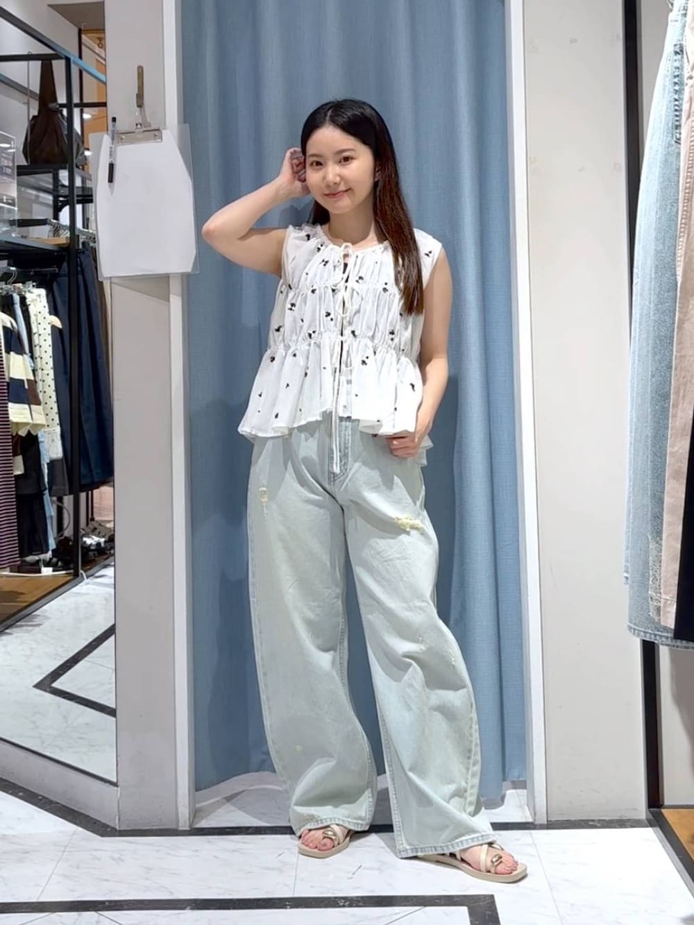 ブルー系のデニムパンツ、ホワイト系のサンダル、ホワイト系のシャツ/ブラウスを着用したレディースの夏コーディネートの3枚目の写真