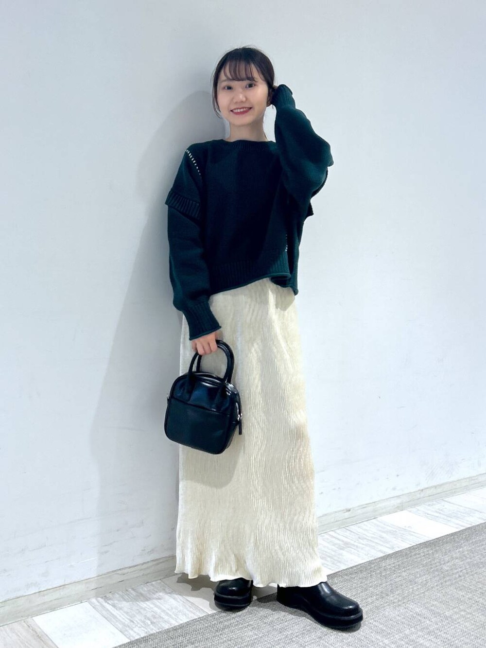 グリーン系のTシャツ/カットソー、ブラック系のブーツ、ブラック系のボストンバッグを着用したレディースの秋コーディネートの3枚目の写真