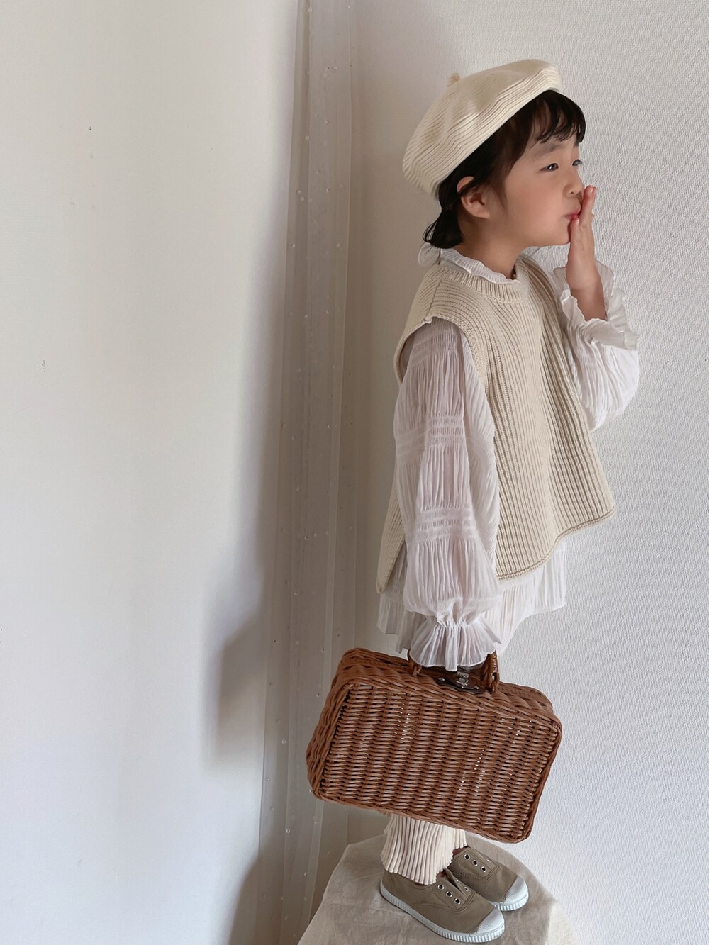 ホワイト系のベスト、ベージュ系のシューズ、ホワイト系のハンチング/ベレー帽を着用したキッズの春コーディネートの4枚目の写真