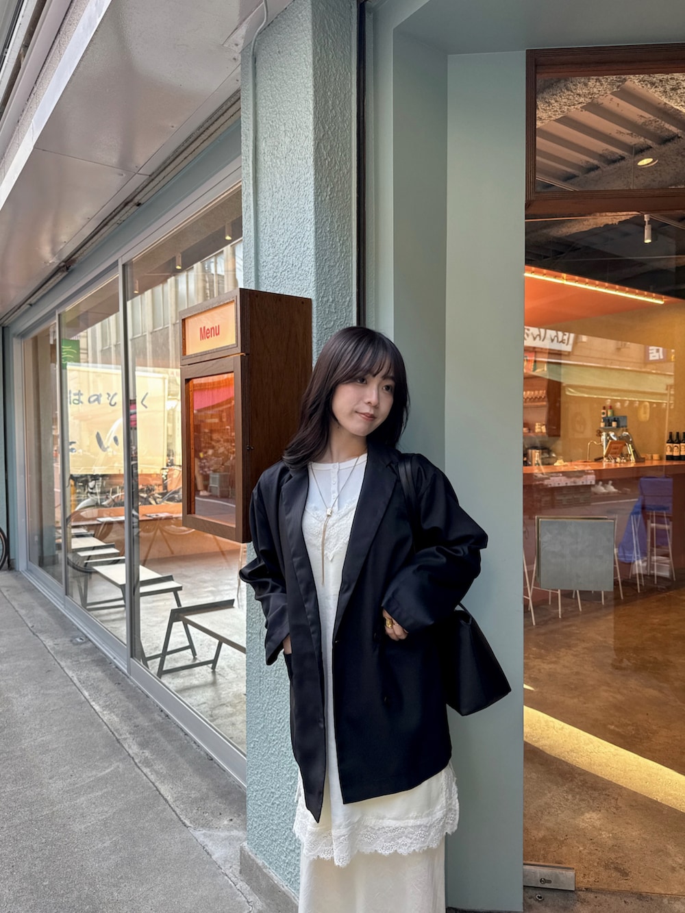 ホワイト系のスカート、ブラック系のテーラードジャケット、ブラック系のハンドバッグを着用したレディースの春コーディネートの3枚目の写真