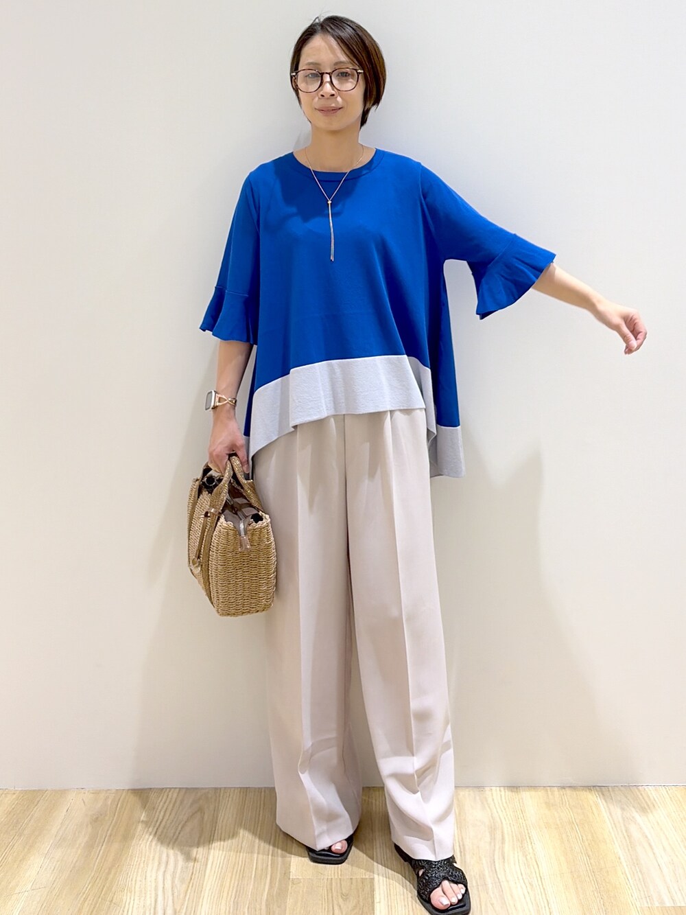 ブルー系のニット/セーター、ベージュ系のその他パンツ、ブラウン系のトートバッグを着用したレディースの夏コーディネートの4枚目の写真