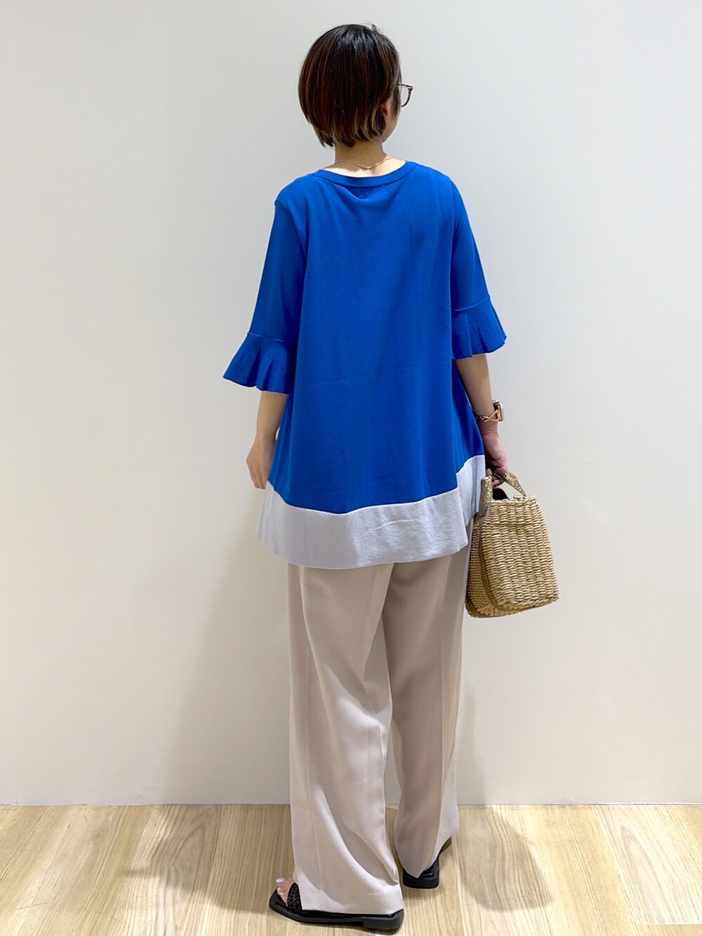 ブルー系のニット/セーター、ベージュ系のその他パンツ、ブラウン系のトートバッグを着用したレディースの夏コーディネートの3枚目の写真
