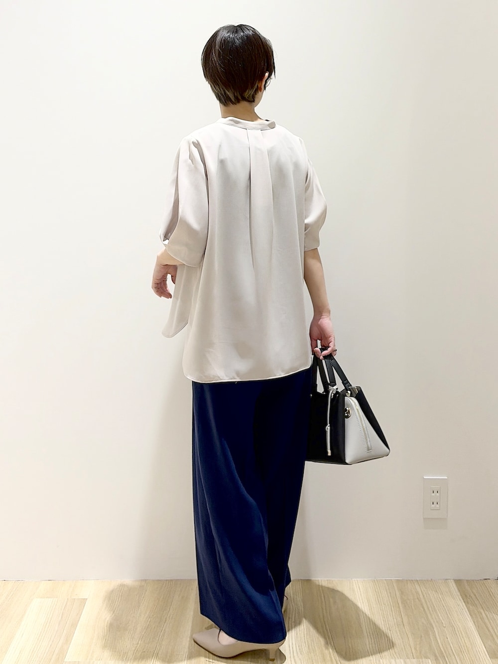 ブラック系のショルダーバッグ、ベージュ系のパンプス、ベージュ系のシャツ/ブラウスを着用したレディースの春コーディネートの3枚目の写真