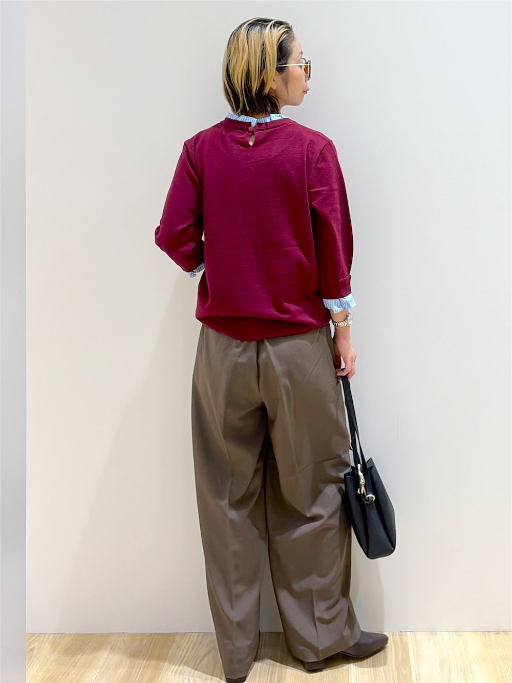 レッド系のニット/セーター、ブラウン系のその他パンツ、ブラック系のショルダーバッグを着用したレディースの秋コーディネートの3枚目の写真