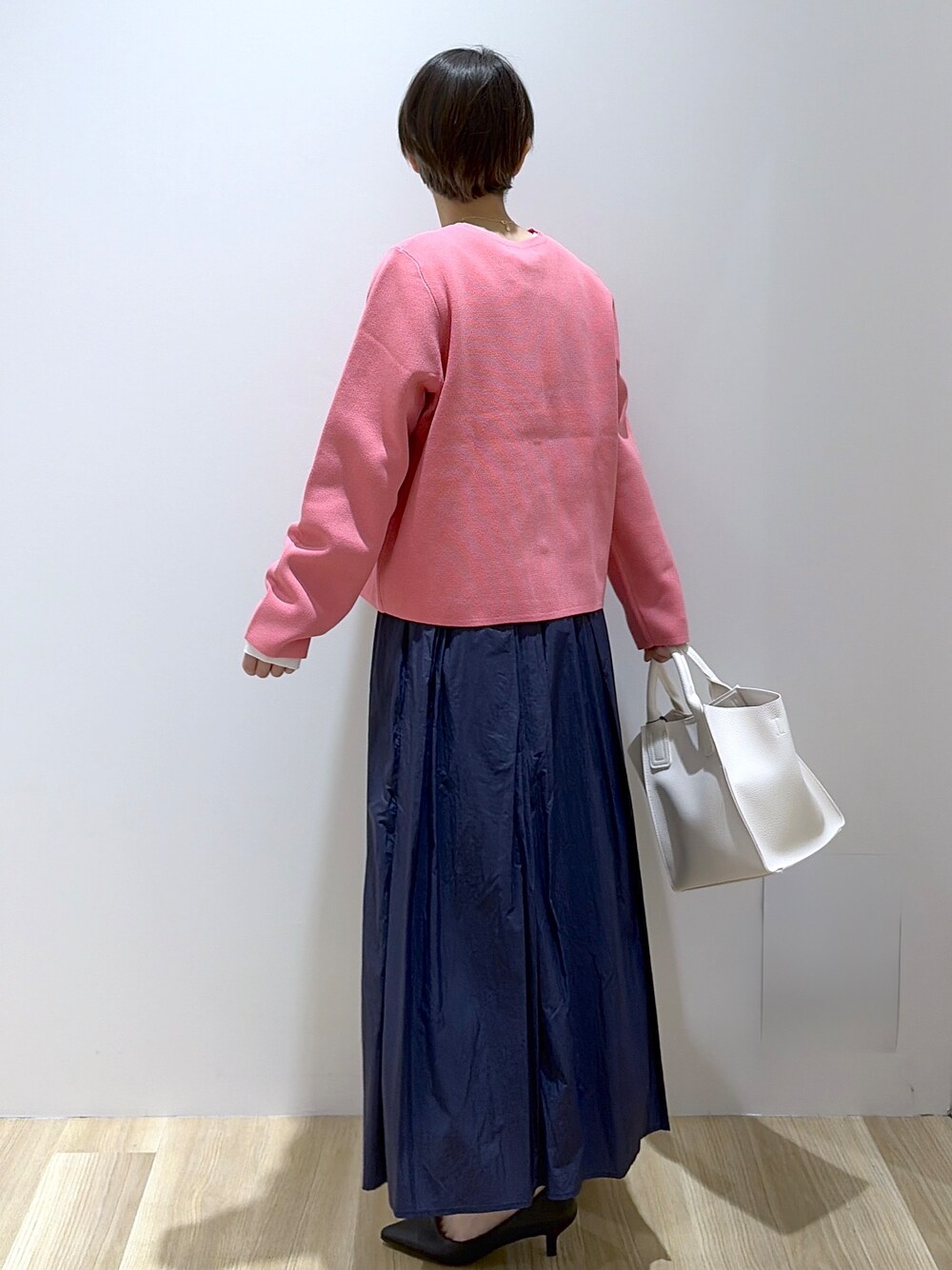ホワイト系のショルダーバッグ、ブラック系のパンプス、ブルー系のスカートを着用したレディースの春コーディネートの2枚目の写真
