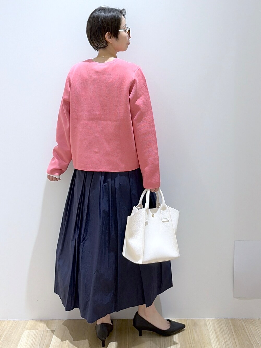 ホワイト系のショルダーバッグ、ブラック系のパンプス、ブルー系のスカートを着用したレディースの春コーディネートの4枚目の写真