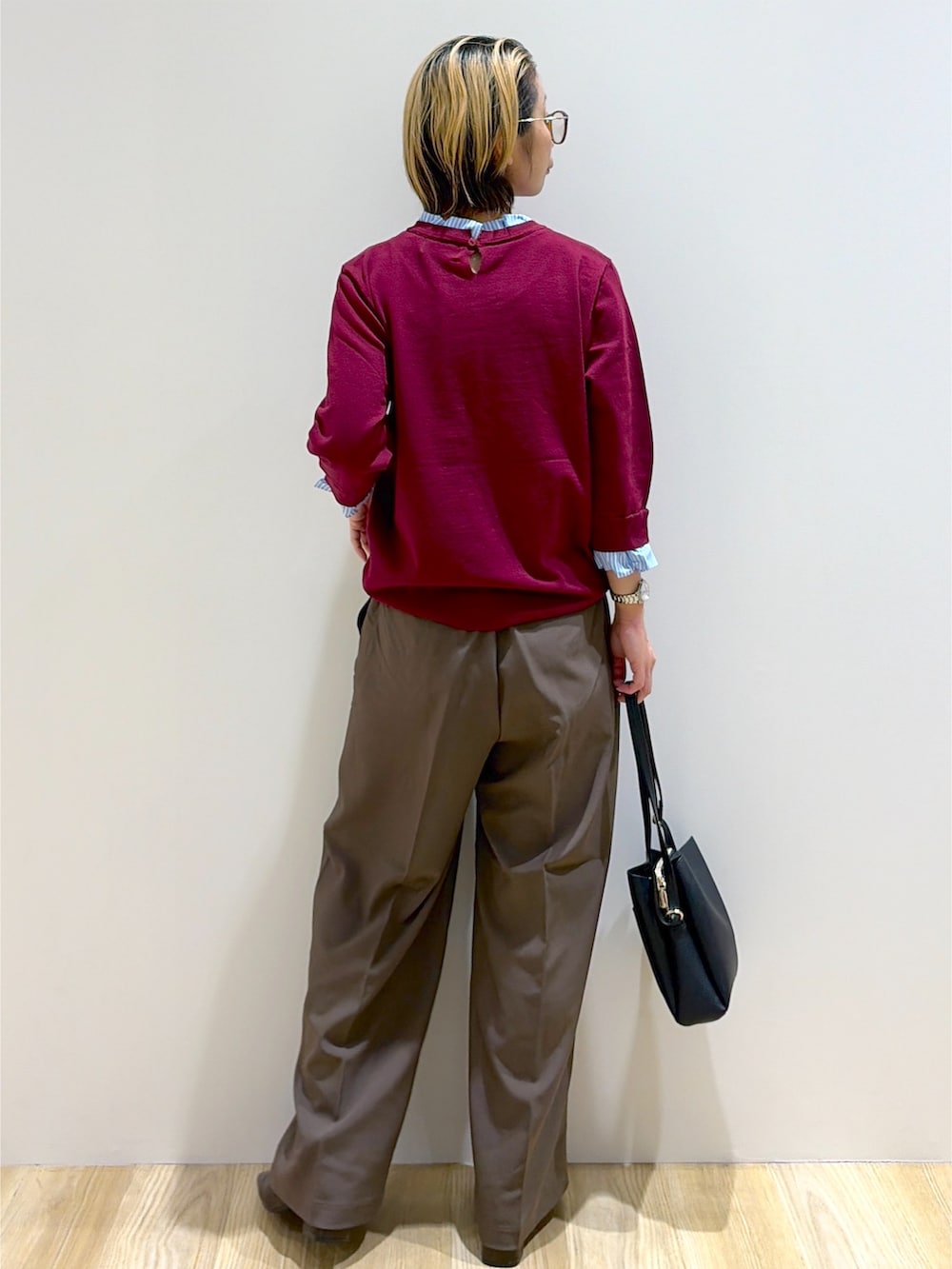 レッド系のニット/セーター、ブラウン系のその他パンツ、ブラック系のショルダーバッグを着用したレディースの秋コーディネートの2枚目の写真