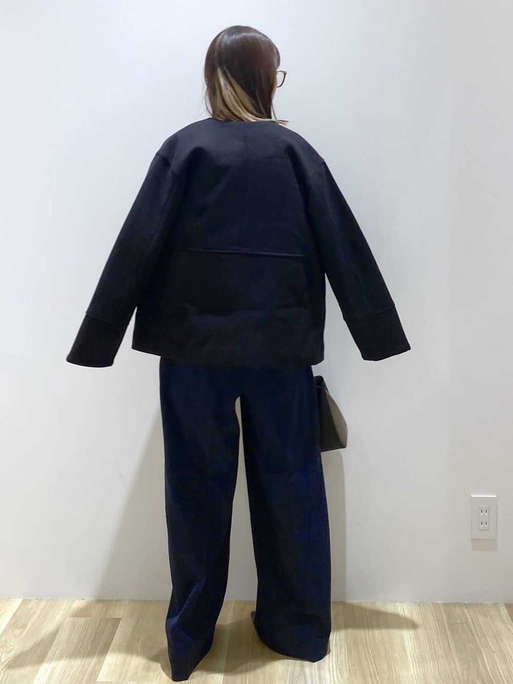 ブラック系のノーカラーコート、ブルー系のニット/セーター、ブルー系のその他パンツを着用したレディースの秋コーディネートの3枚目の写真