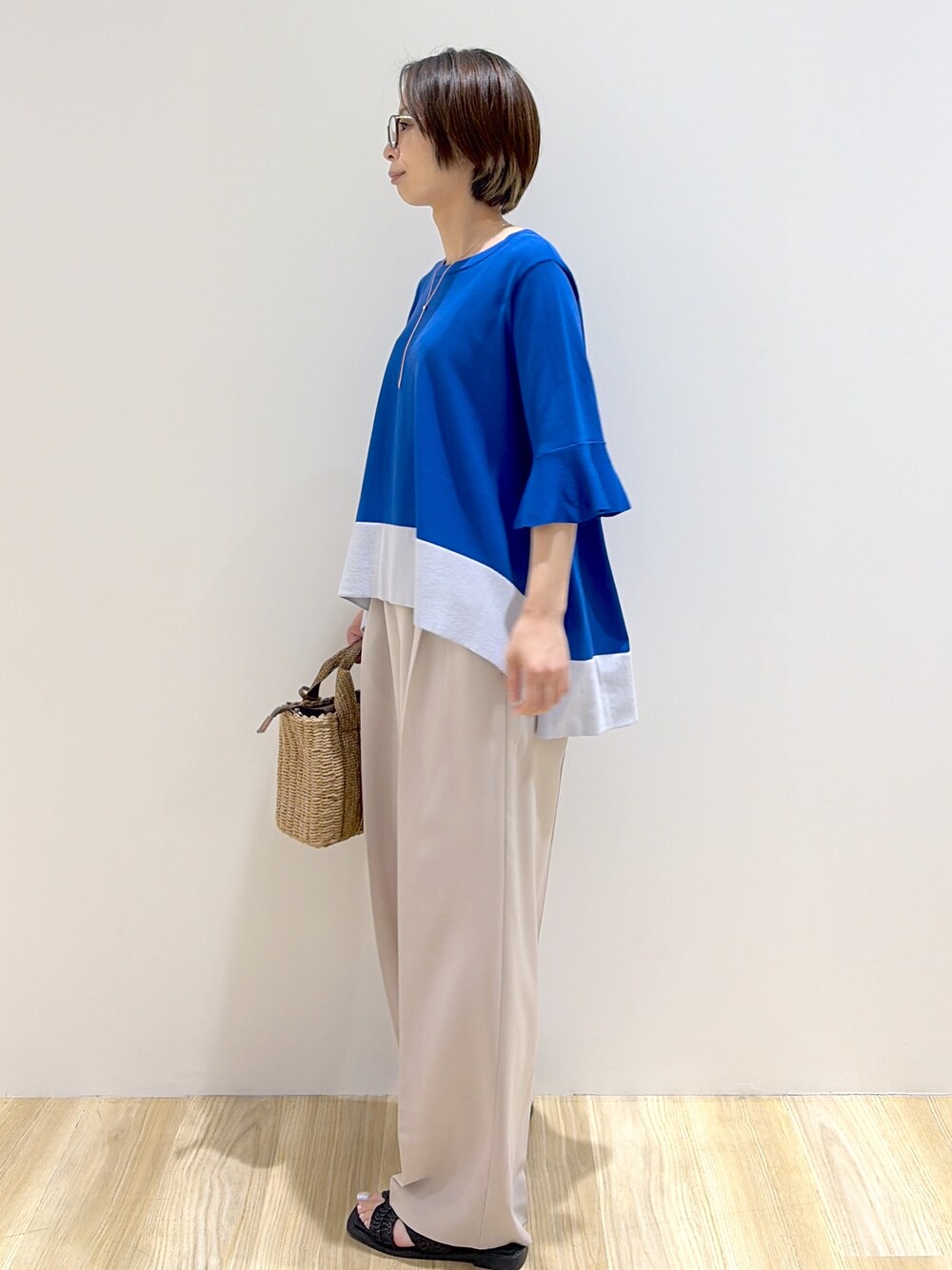 ブルー系のニット/セーター、ベージュ系のその他パンツ、ブラウン系のトートバッグを着用したレディースの夏コーディネートの2枚目の写真