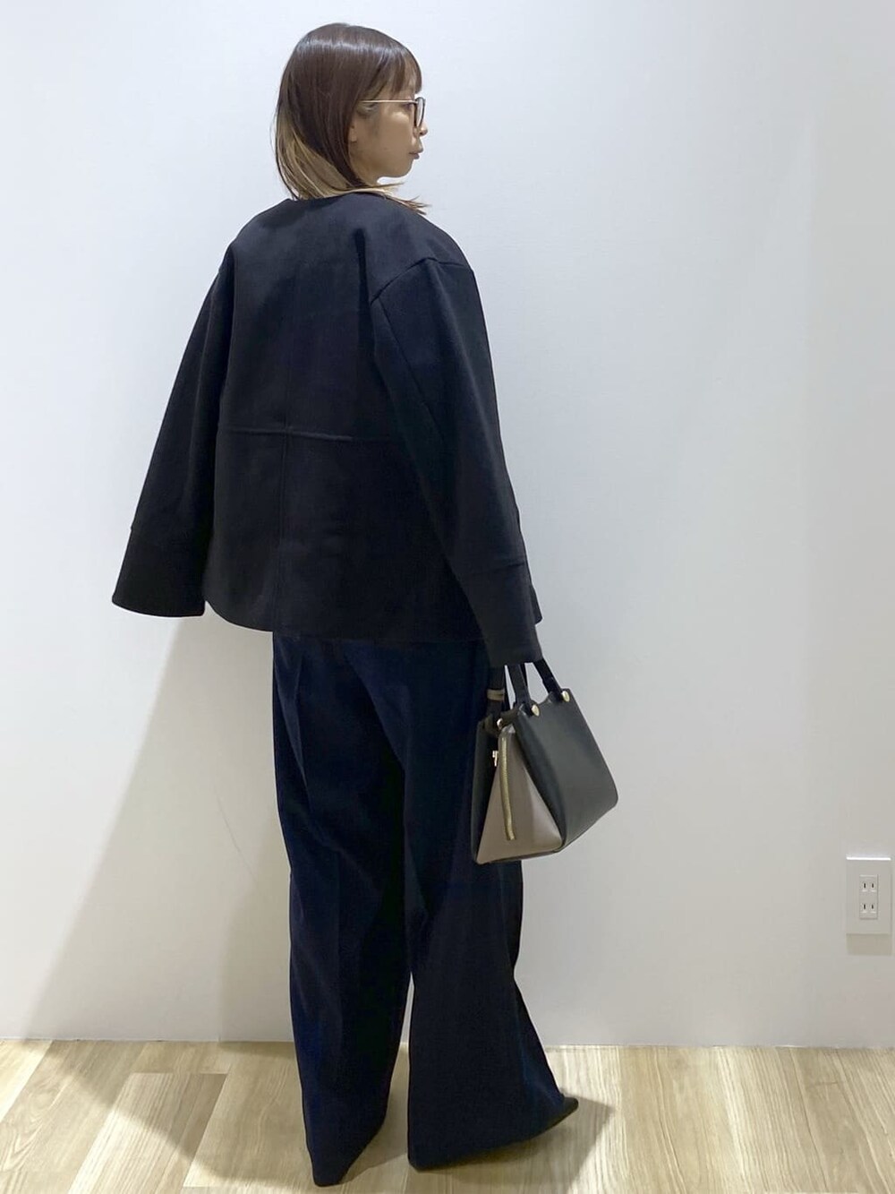 ブラック系のノーカラーコート、ブルー系のニット/セーター、ブルー系のその他パンツを着用したレディースの秋コーディネートの4枚目の写真