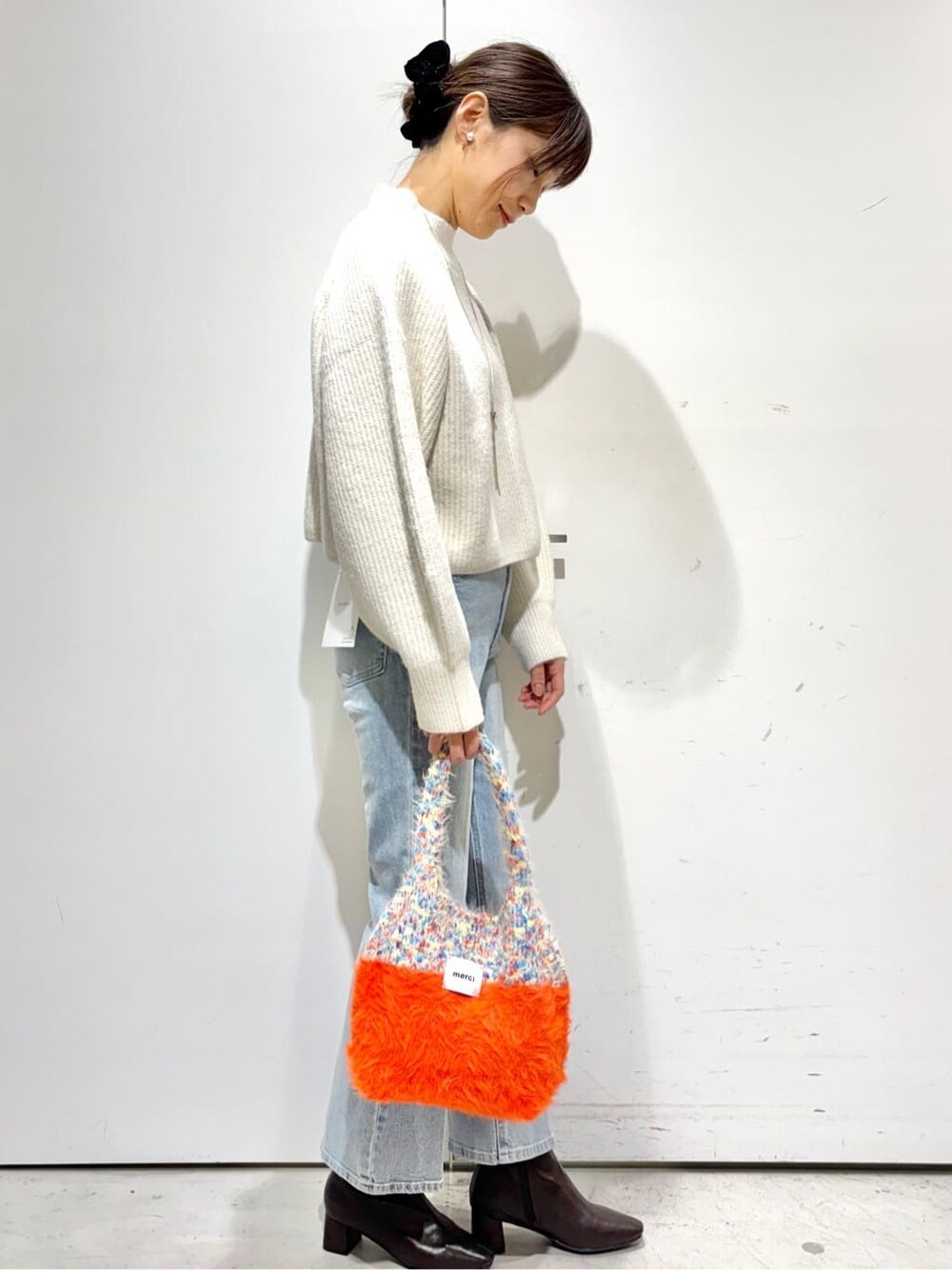 ホワイト系のニット/セーター、ブルー系のデニムパンツ、オレンジ系のトートバッグを着用したレディースの冬コーディネートの3枚目の写真