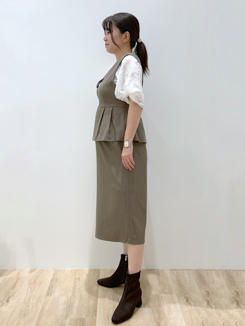 ブラウン系のワンピース、ホワイト系のTシャツ/カットソー、ブラウン系のブーツを着用したレディースの秋コーディネートの2枚目の写真