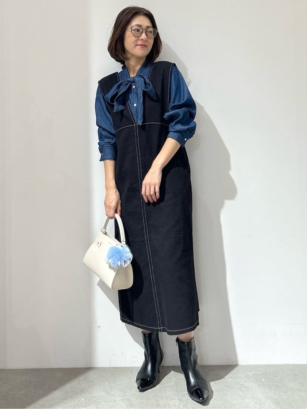 ブルー系のシャツ/ブラウス、ブラック系のワンピース、ホワイト系のショルダーバッグを着用したレディースの秋コーディネートの2枚目の写真