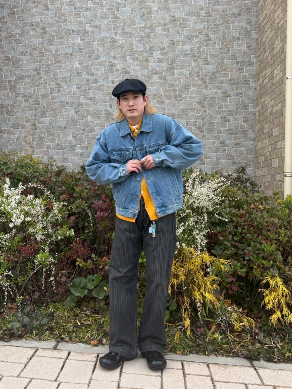 イエロー系のニット/セーター、ブルー系のデニムジャケット、ブラック系のシューズを着用したメンズの春コーディネートの2枚目の写真