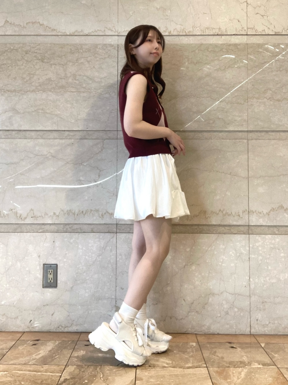 レッド系のニット/セーター、ホワイト系のスカート、ホワイト系のサンダルを着用したレディースの夏コーディネートの3枚目の写真