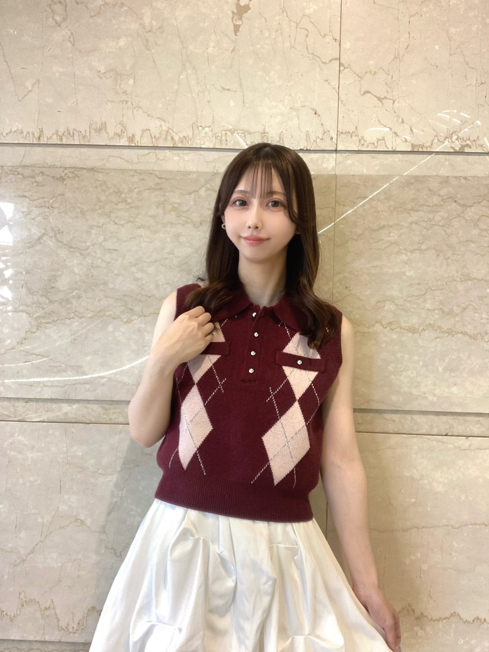 レッド系のニット/セーター、ホワイト系のスカート、ホワイト系のサンダルを着用したレディースの夏コーディネートの5枚目の写真