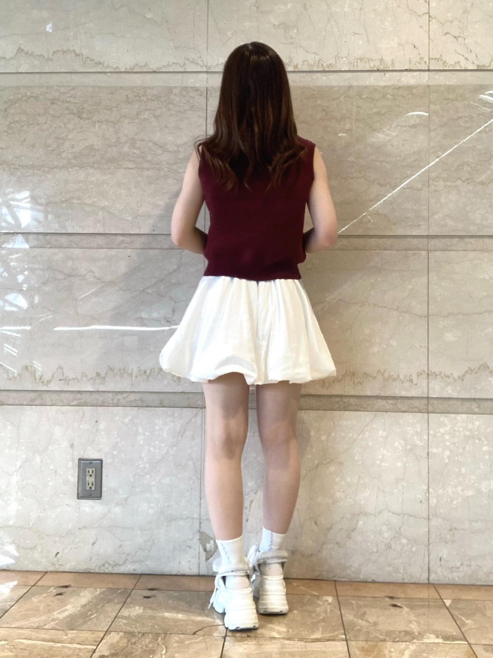 レッド系のニット/セーター、ホワイト系のスカート、ホワイト系のサンダルを着用したレディースの夏コーディネートの4枚目の写真
