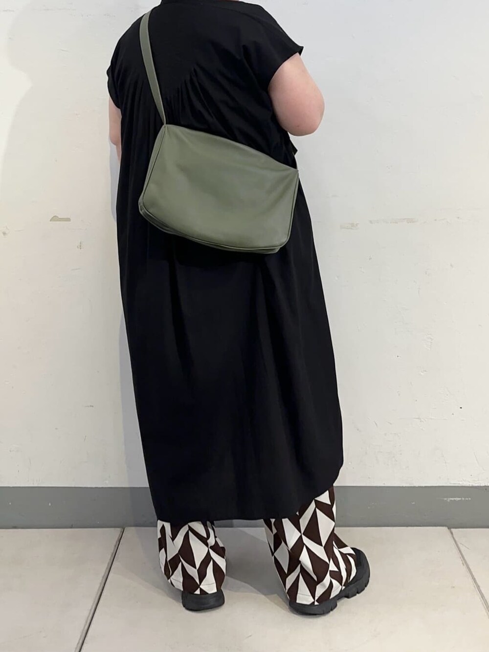 グリーン系のショルダーバッグを着用したレディースの秋コーディネートの2枚目の写真