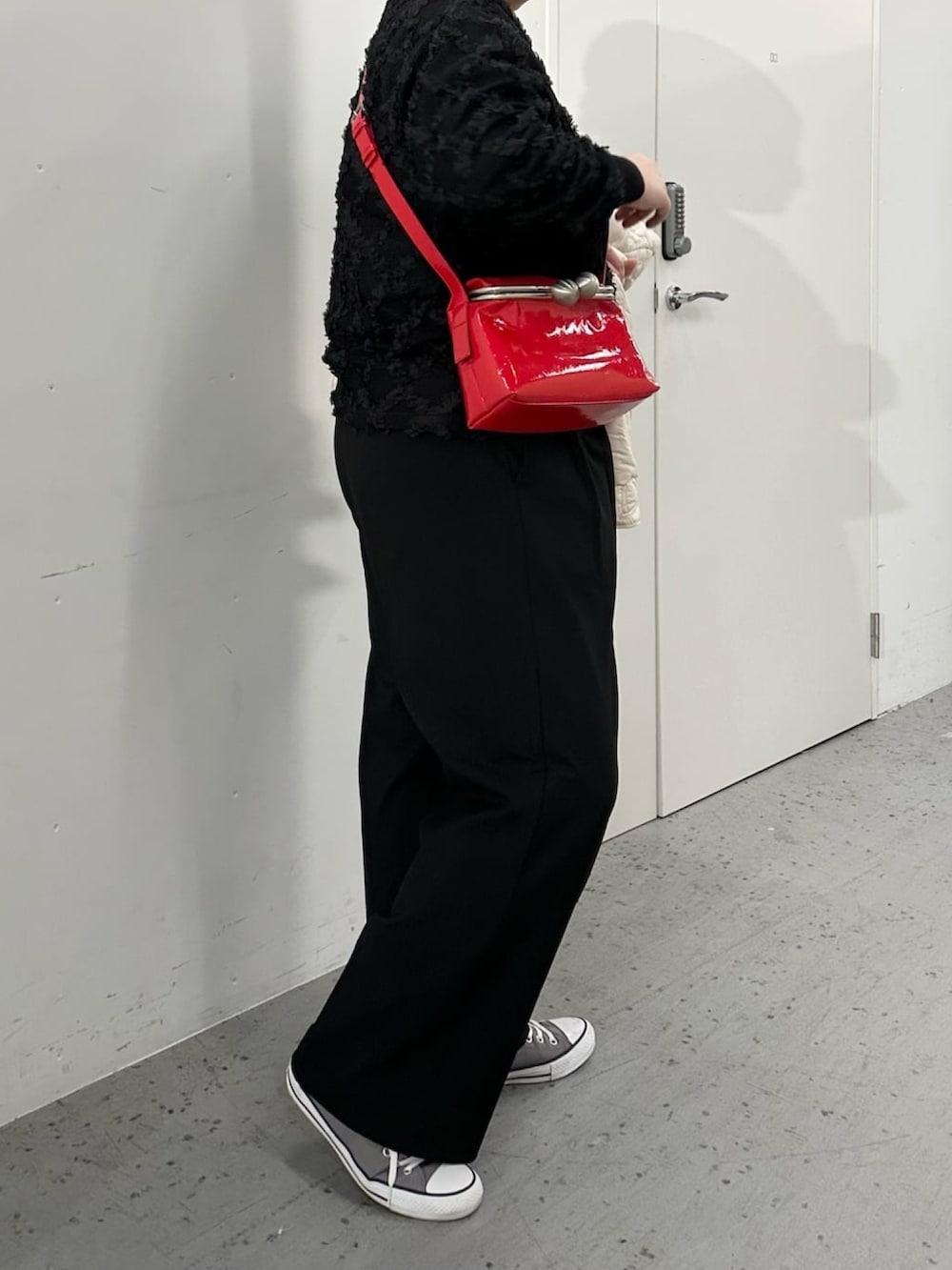 レッド系のショルダーバッグ、ブラック系のTシャツ/カットソーを着用したレディースの冬コーディネートの2枚目の写真