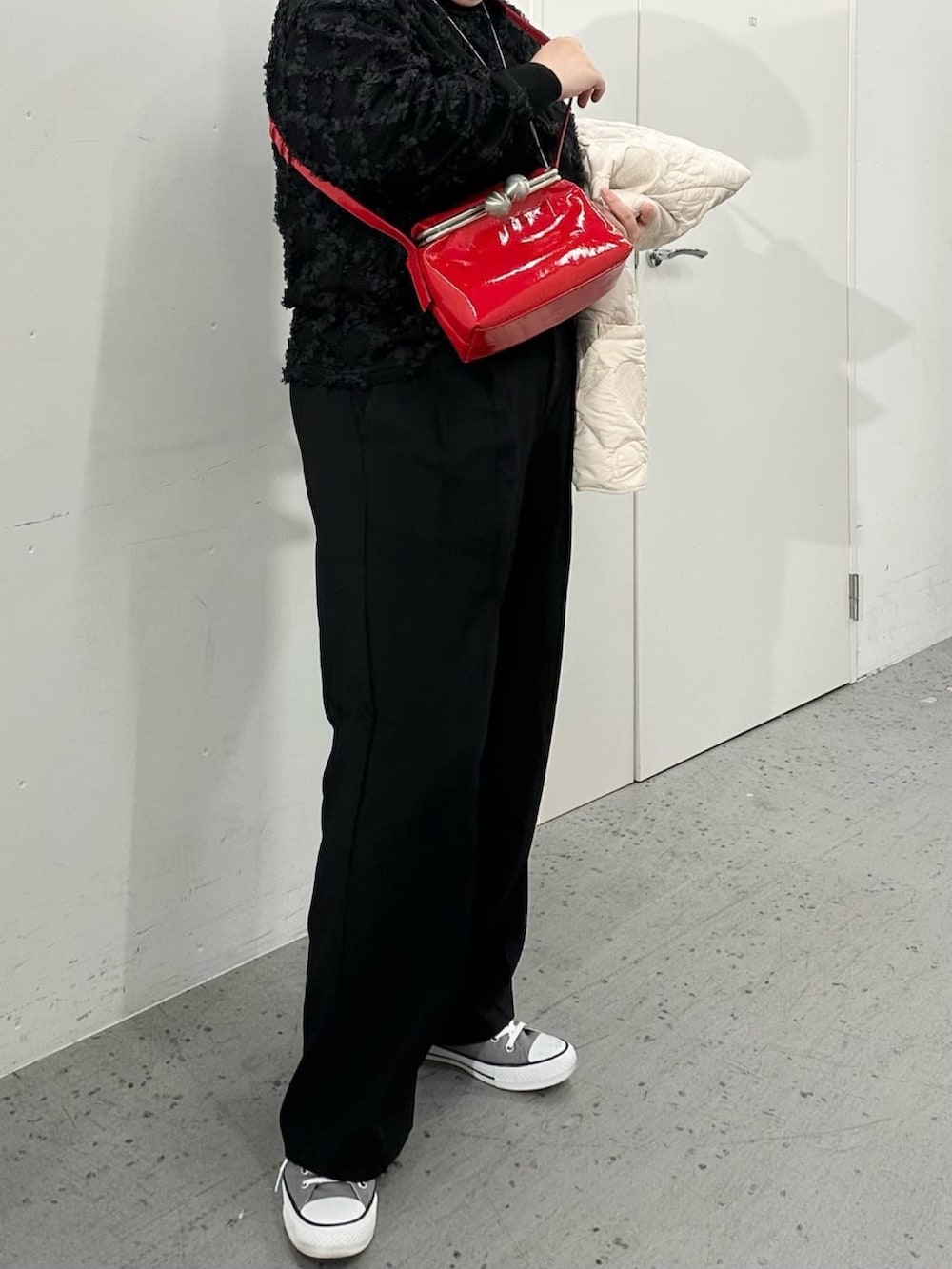 レッド系のショルダーバッグ、ブラック系のTシャツ/カットソーを着用したレディースの冬コーディネートの3枚目の写真