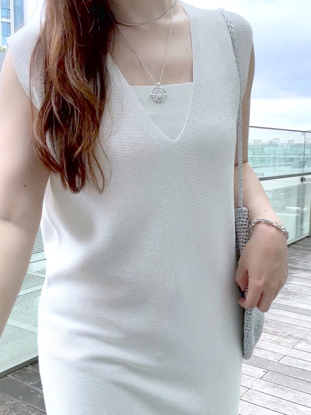 ホワイト系のワンピース、ブルー系のデニムパンツ、シルバー系のショルダーバッグを着用したレディースの夏コーディネートの5枚目の写真
