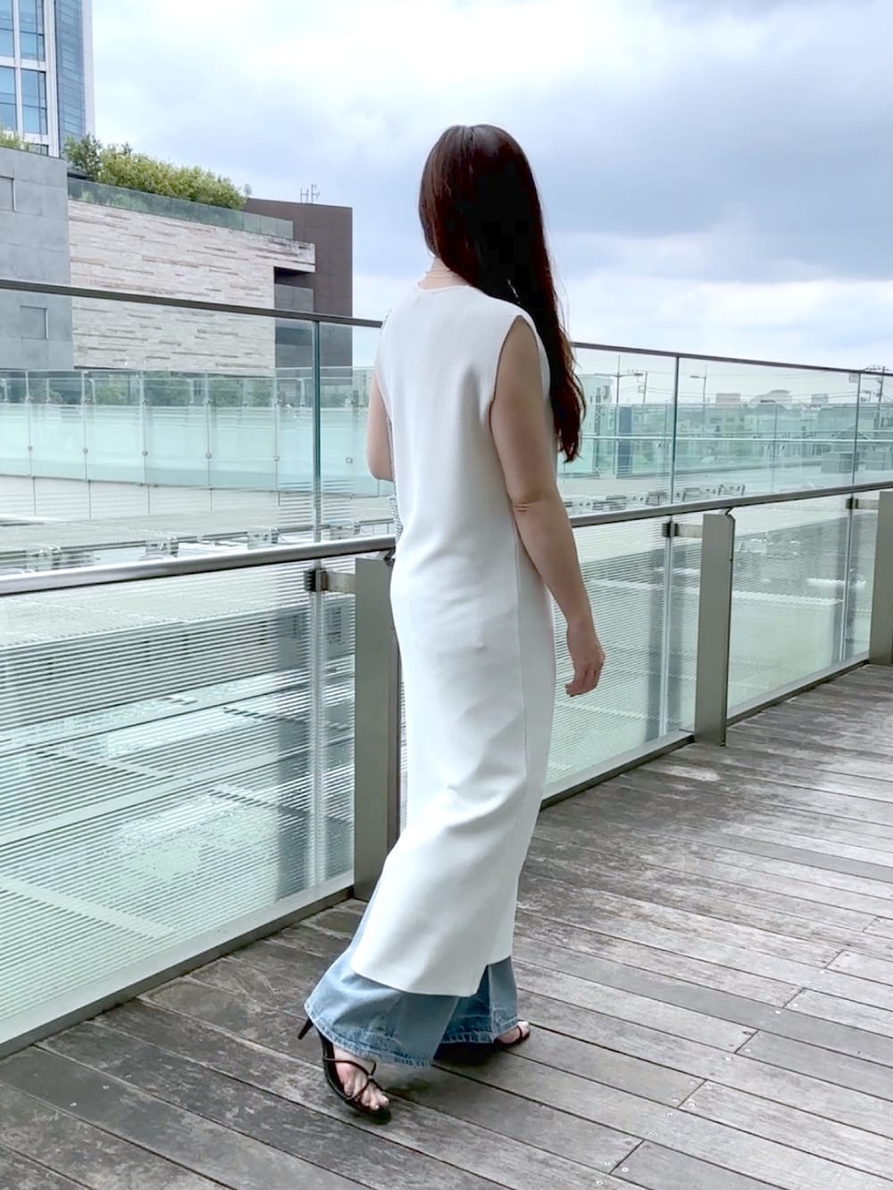 ホワイト系のワンピース、ブルー系のデニムパンツ、シルバー系のショルダーバッグを着用したレディースの夏コーディネートの4枚目の写真