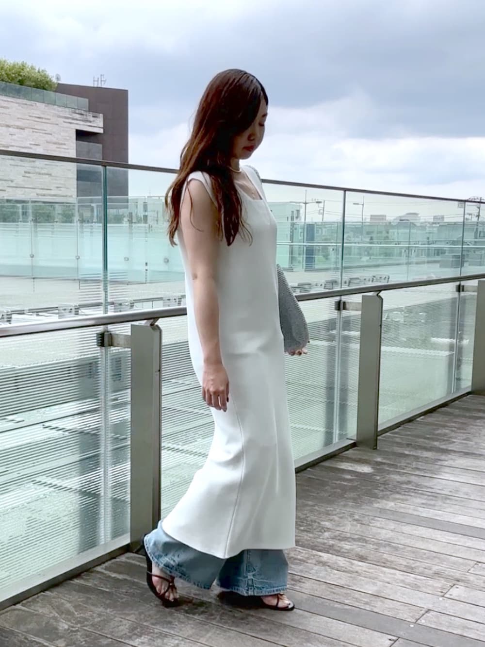 ホワイト系のワンピース、ブルー系のデニムパンツ、シルバー系のショルダーバッグを着用したレディースの夏コーディネートの2枚目の写真