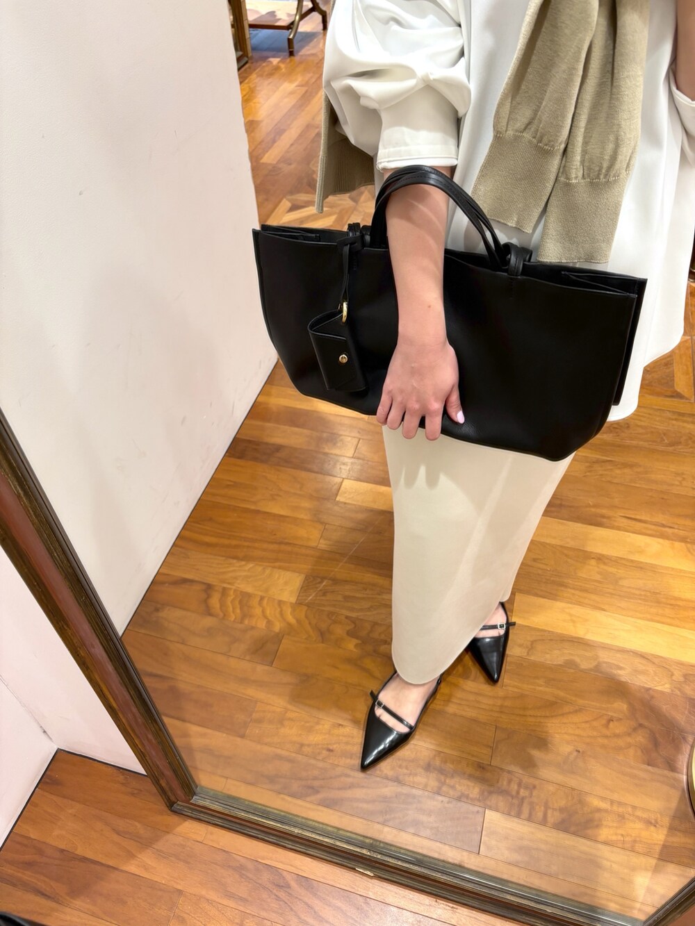 ホワイト系のシャツ/ブラウス、ホワイト系のスカート、ブラック系のトートバッグを着用したレディースの冬コーディネートの4枚目の写真