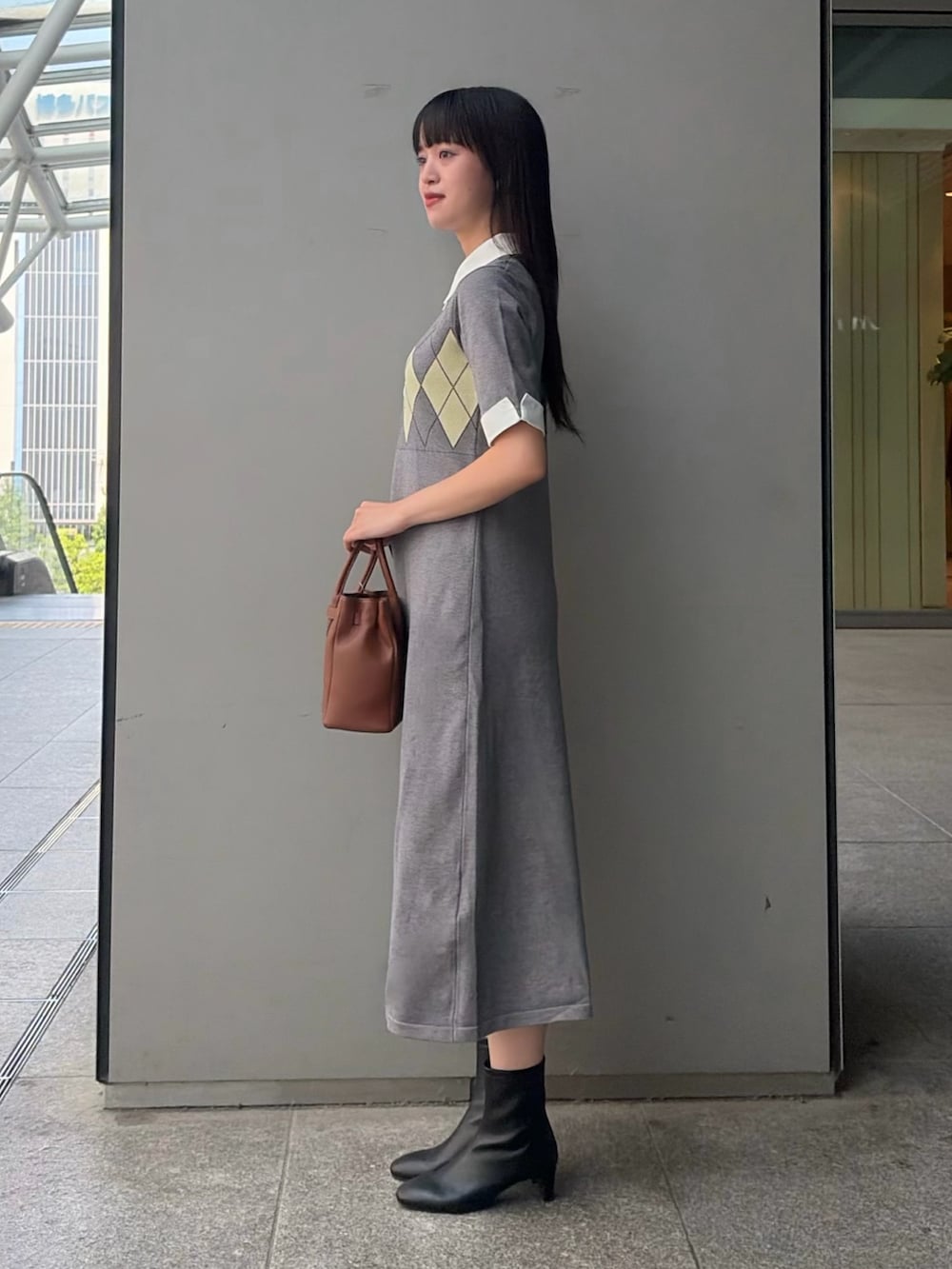 グレー系のワンピース、イエロー系のトートバッグ、ブラック系のブーツを着用したレディースの夏コーディネートの3枚目の写真