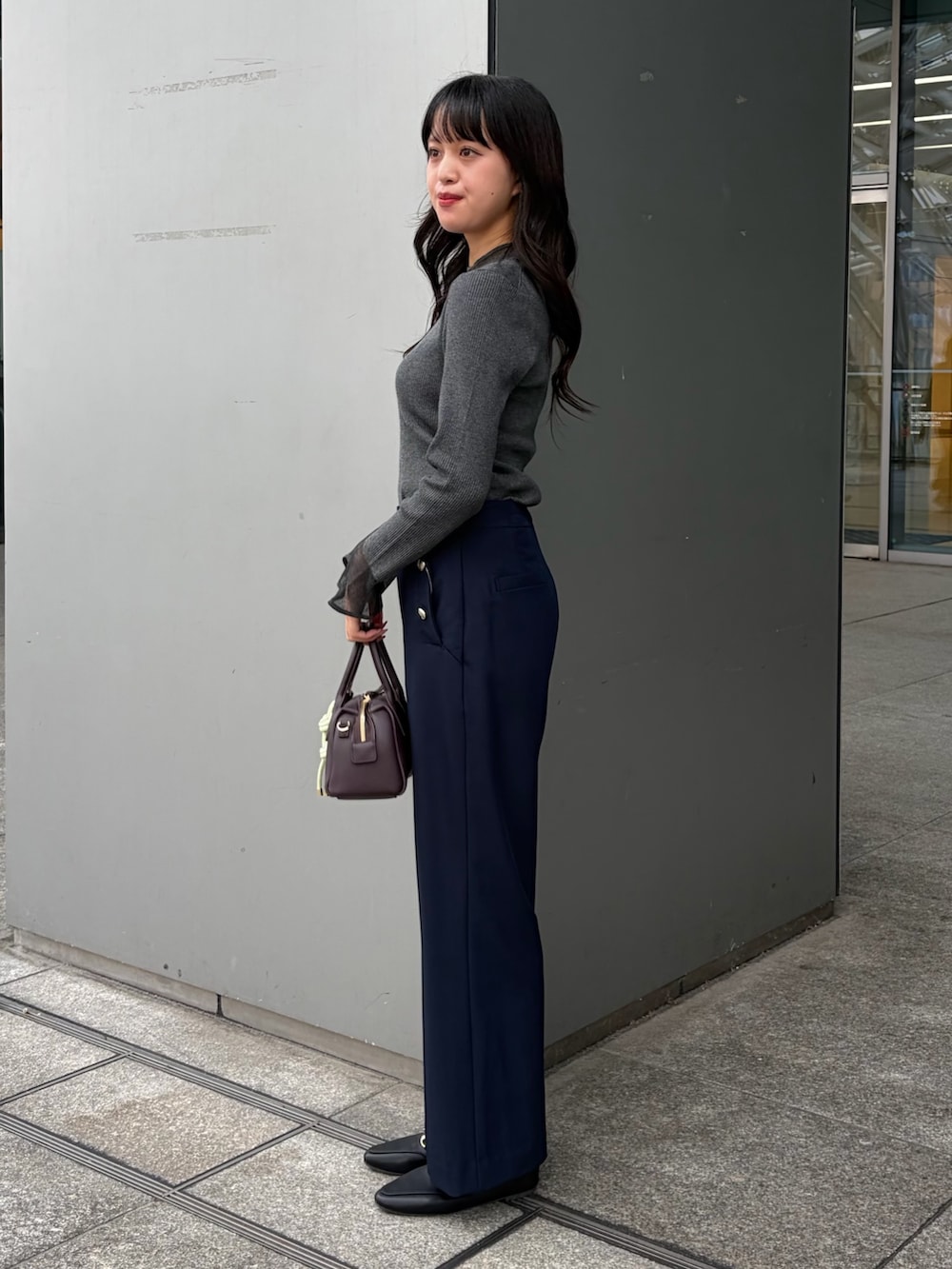 グレー系のニット/セーター、ブルー系のその他パンツ、ブラウン系のボストンバッグを着用したレディースの秋コーディネートの3枚目の写真