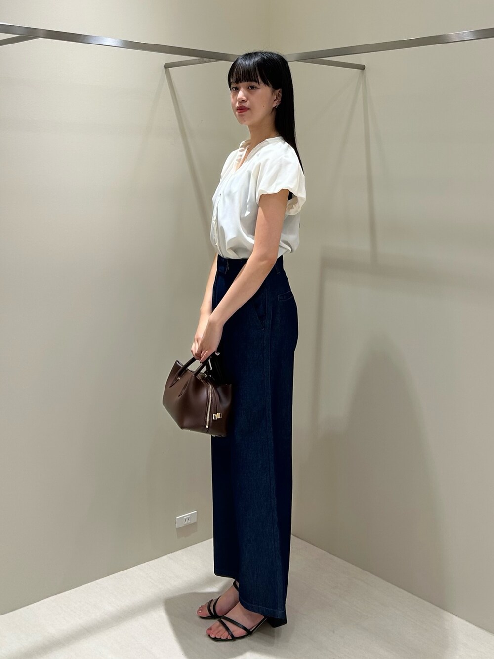ホワイト系のシャツ/ブラウス、ブルー系のデニムパンツ、ブラック系のボストンバッグを着用したレディースの夏コーディネートの4枚目の写真