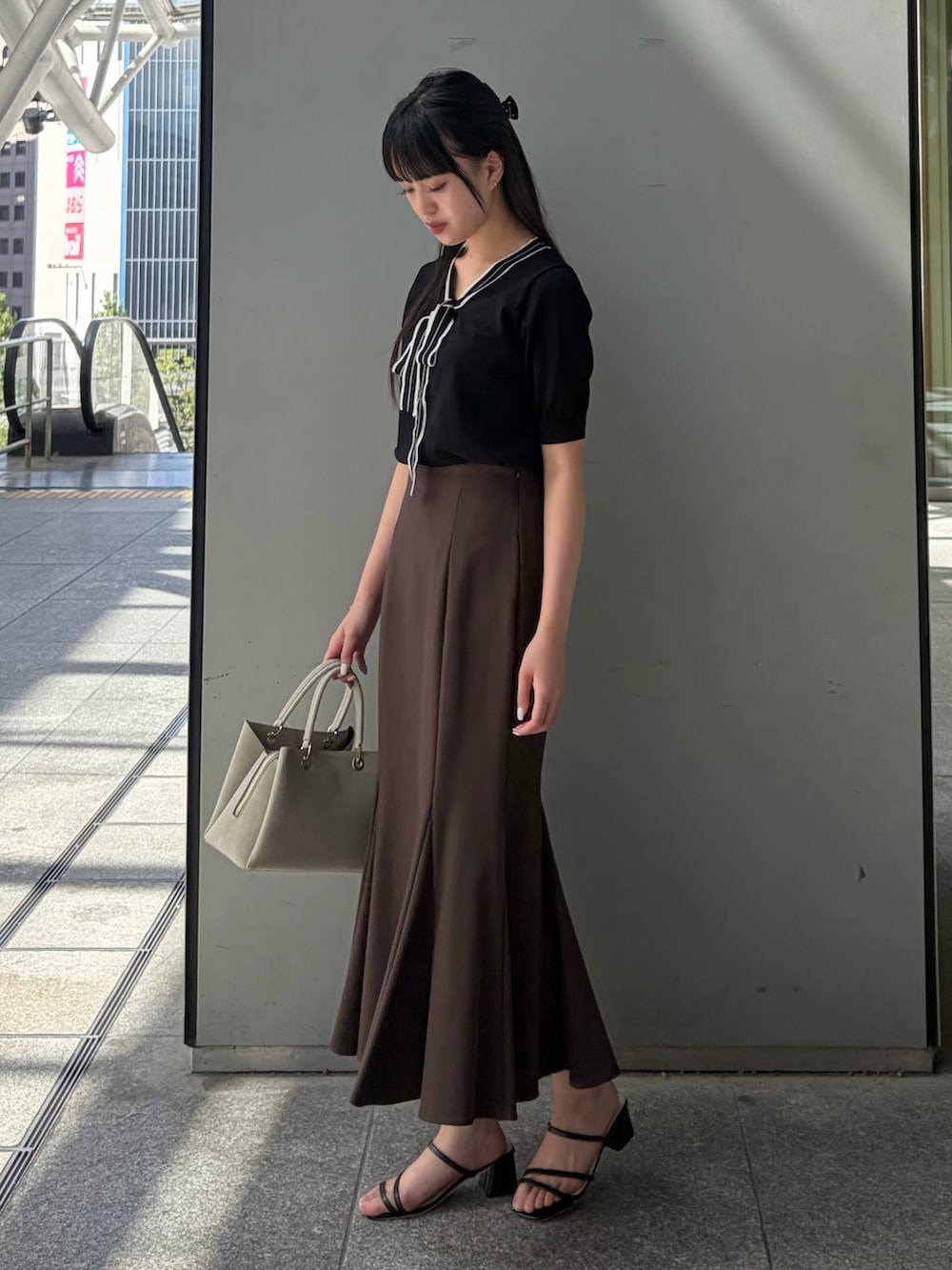ブラック系のニット/セーター、ブラウン系のスカート、ベージュ系のトートバッグを着用したレディースの夏コーディネートの4枚目の写真